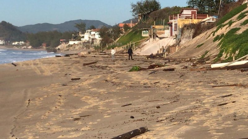 Pedaços de madeira ficaram espalhados pela areia após uma cerca de contenção, construída na beira da praia, ser destruída pelo avanço do mar. - Anderson Coelho/ND